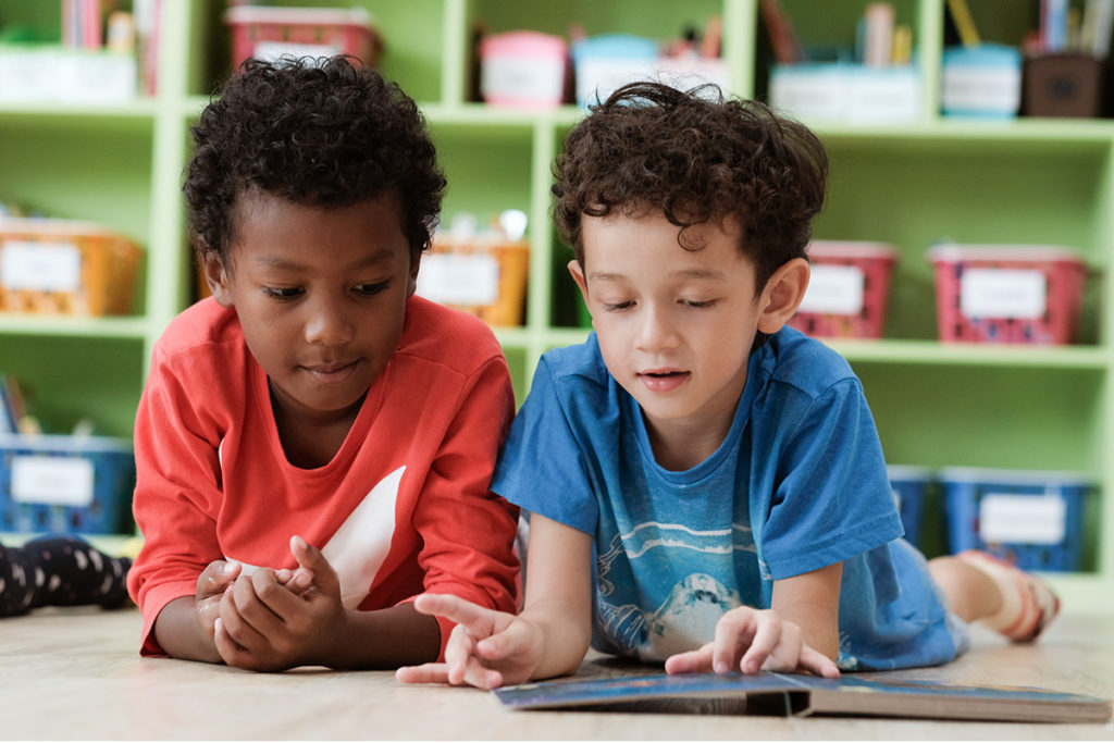 Two preschool boys reading together.