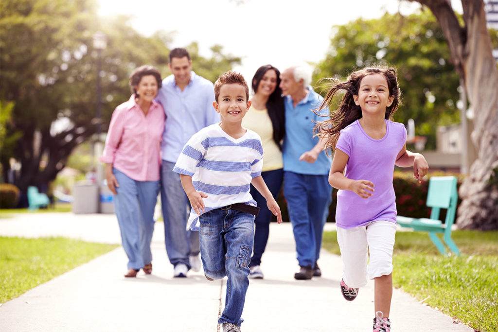 Two children running ahead of their parents and grandparents on a walk.