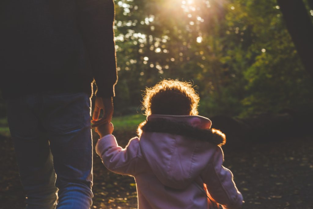 Child holding her dad's hand on a walk.