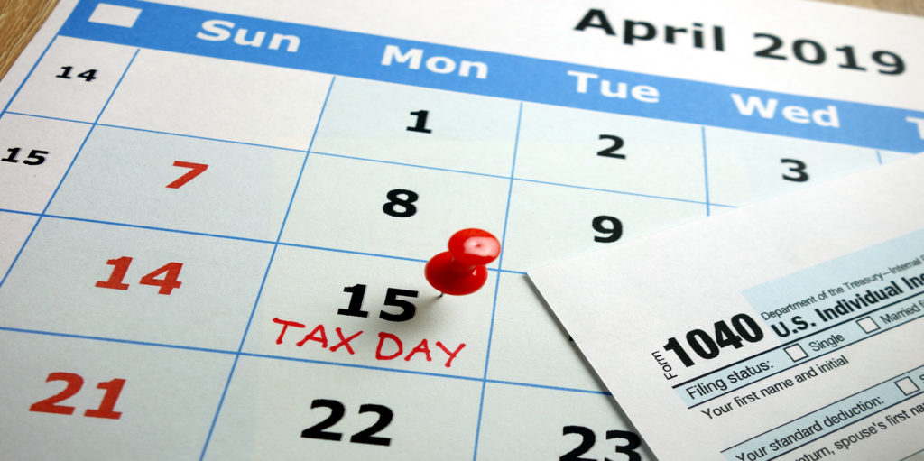 Tax Day marked on April 2019 monthly calendar with 1040 form.