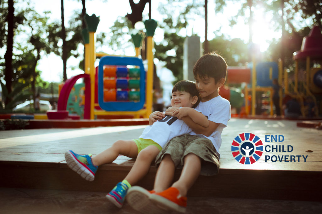 Two young brothers hugging at the playground.