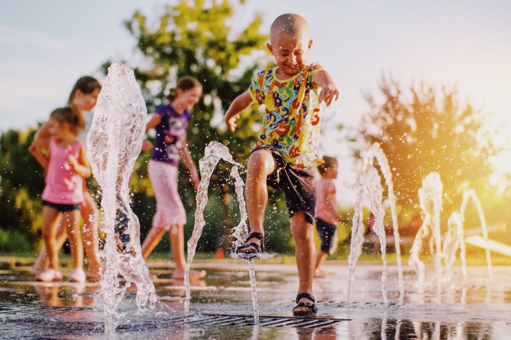 Boy playing in a fountain with friends.
