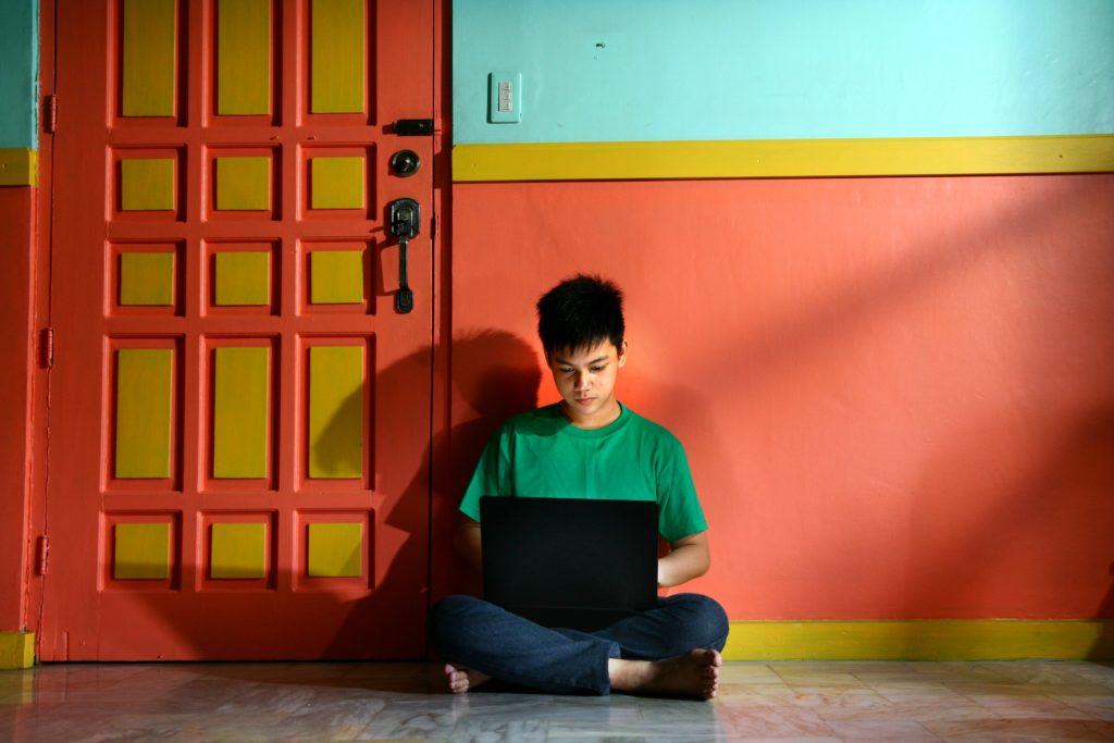 Queer teen using a laptop.