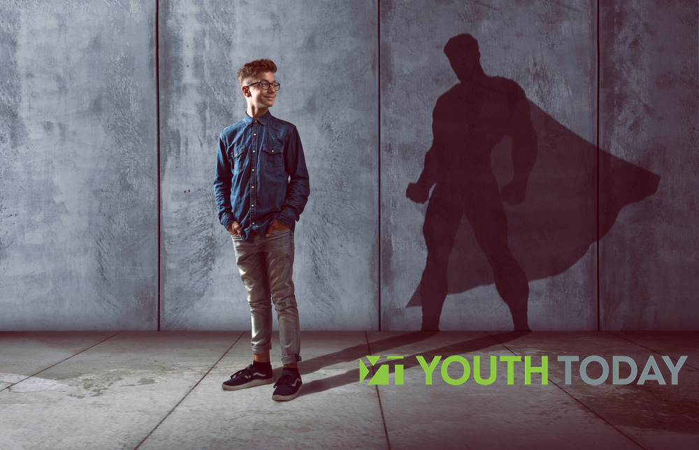 Teen boy in front of a shadow of a superhero.