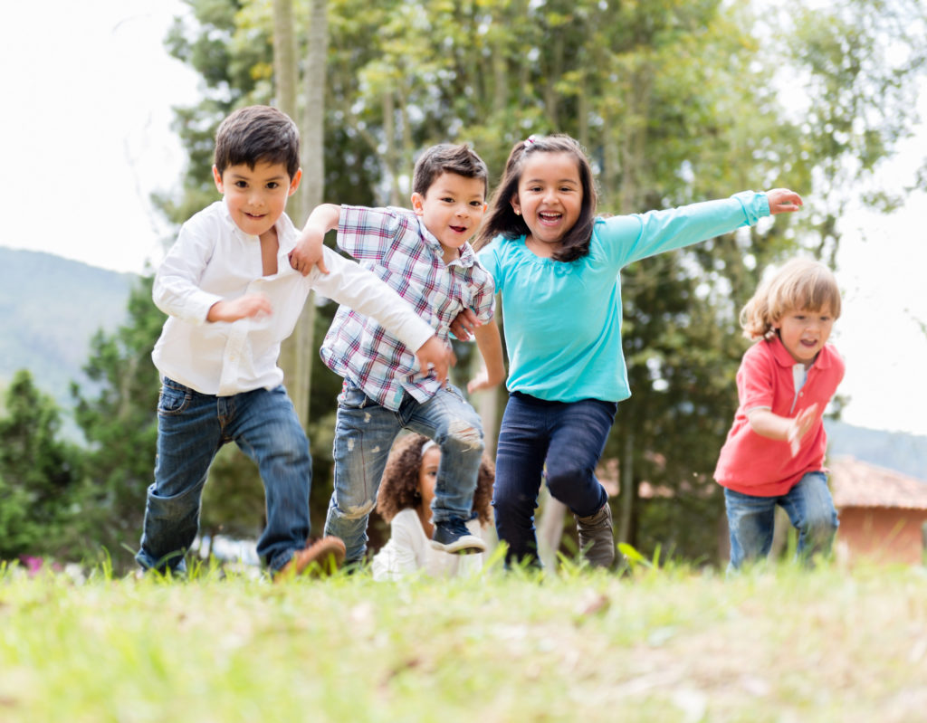 Group of children running through a field.