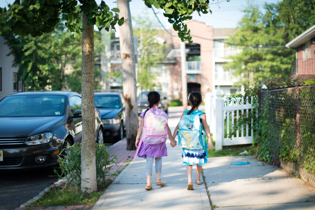 Children with backpacks walking hand-in-hand.