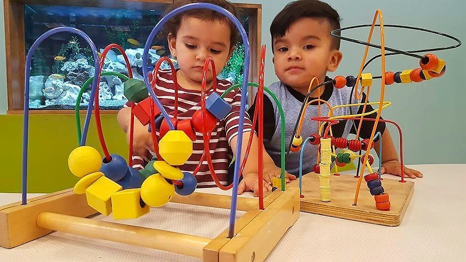Hispanic toddler girl and boy playing with educational toys at a Children's Museum.