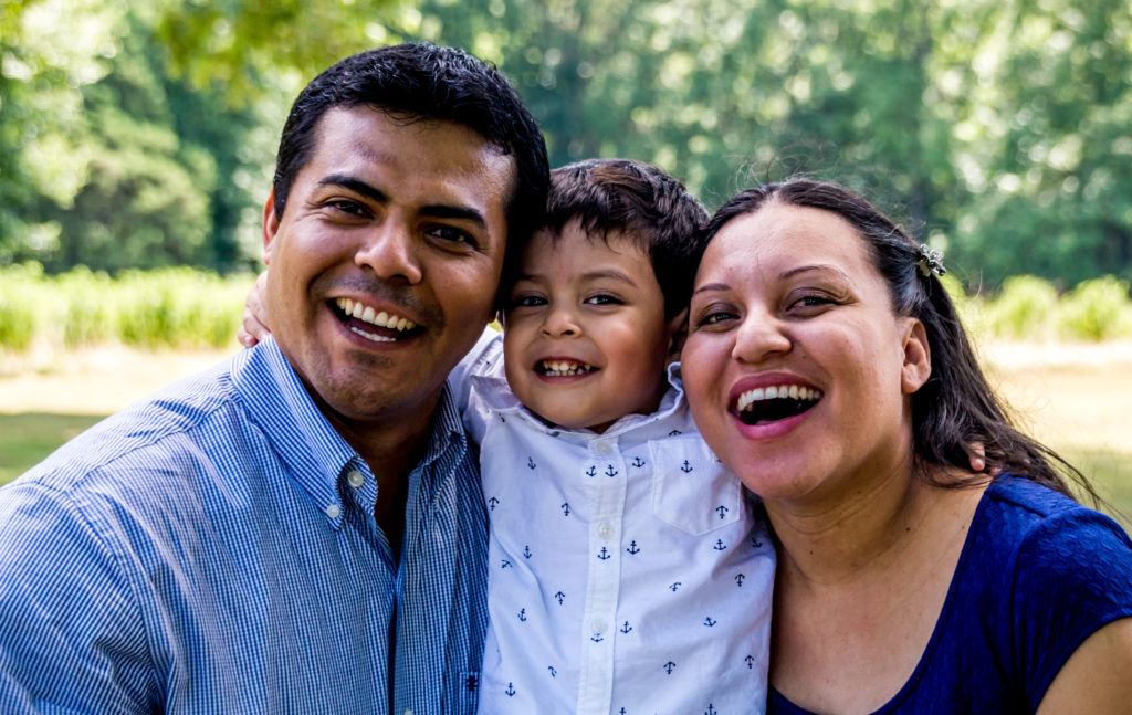 Latino parents with their son smiling and laughing.