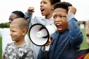 Young,boy,shouting,on,a,megaphone,in,a,protest