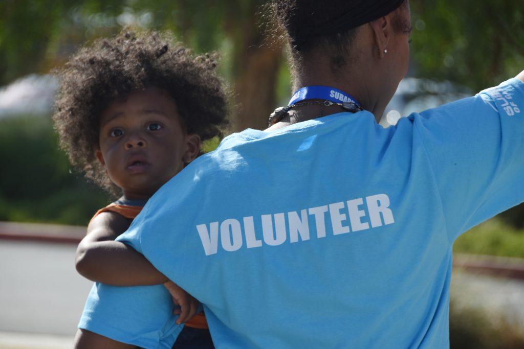 Woman with shirt reading "Volunteer" holding a child.