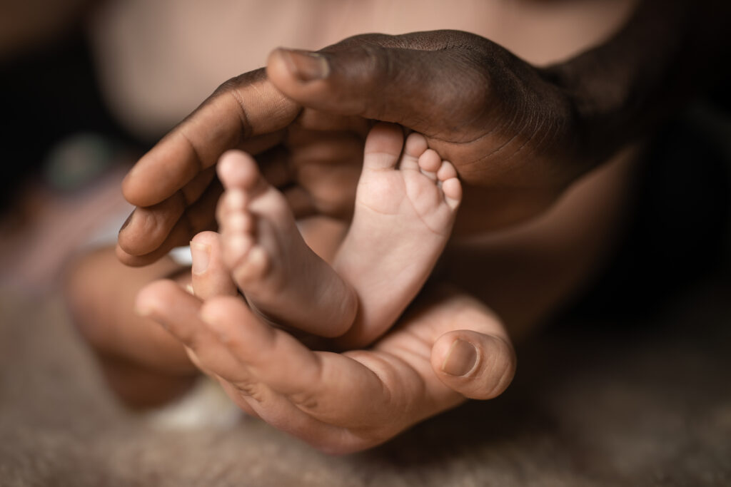 Interracial,family,holding,baby,feet,in,hands,mixed,by,black