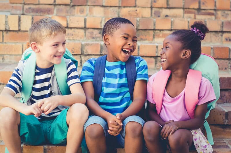 Early Childhood three multiracial kids sitting and laughing