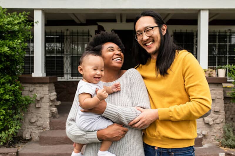 Econimic Security Happy multiethnic family standing in front of the house.