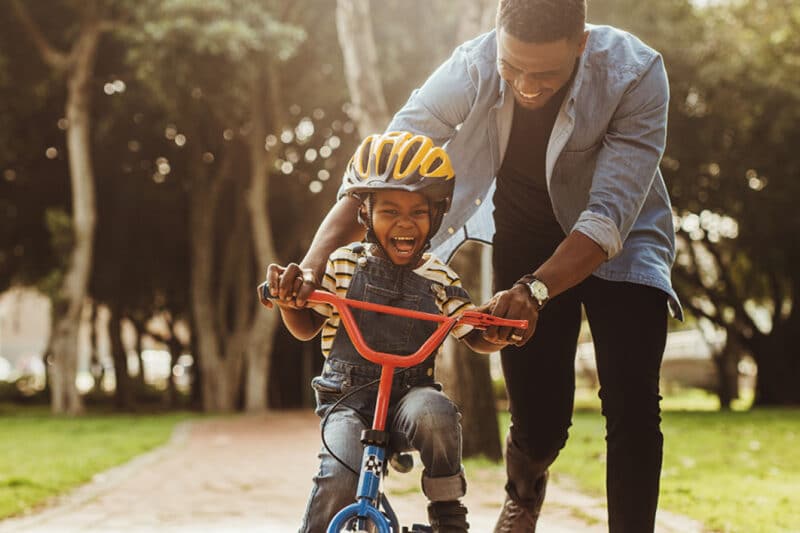 Health and Wellbeing Father teaching son how to ride a bike.