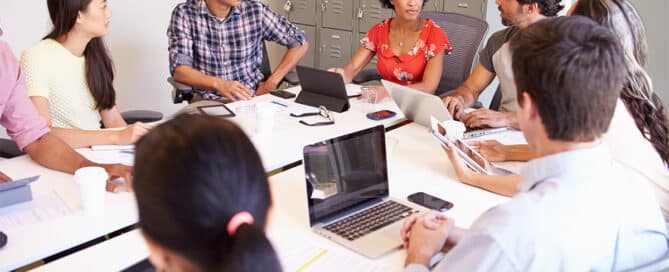 Collaborative work group meeting at a table with laptops.