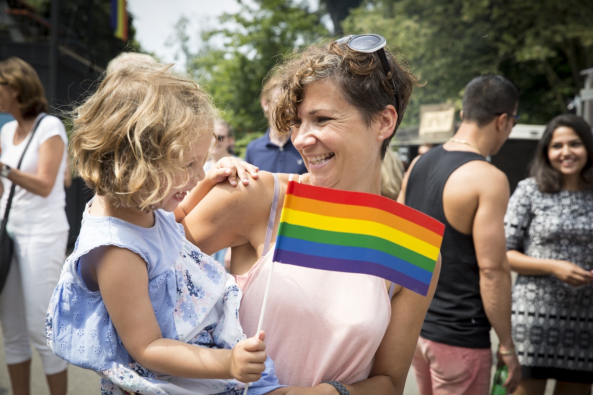 Mother holding daughter with a LGBTQIA+ flag.