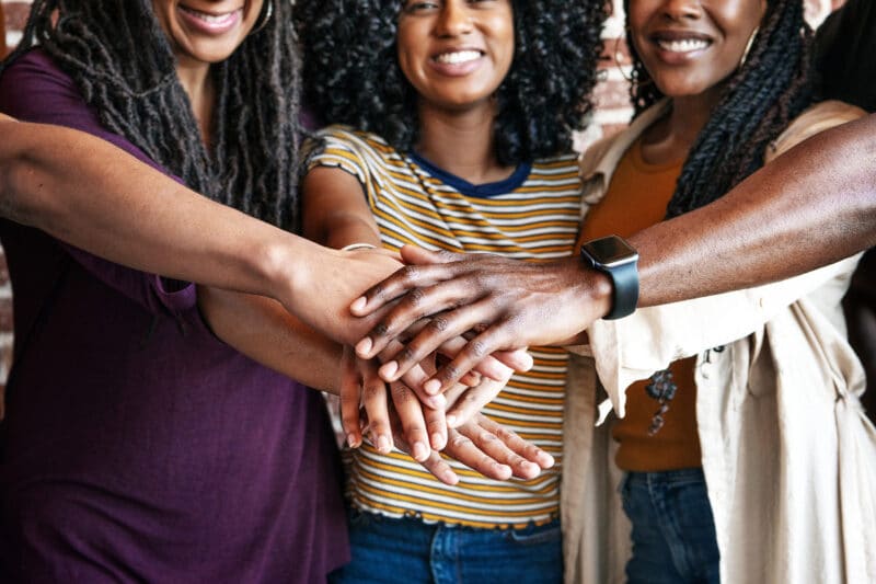 Racial Equity and Justice A group of friends bringing in their hands togetherr in unity.