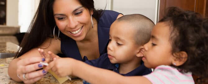 Mother coloring Easter eggs with her two young children.