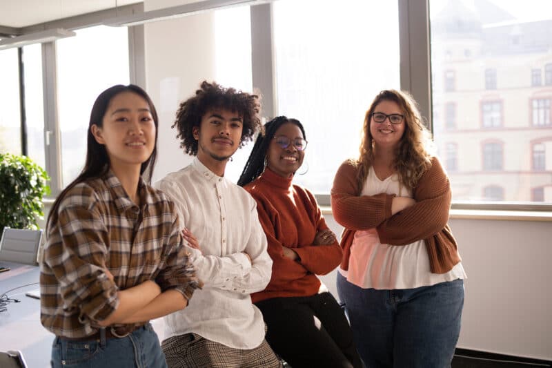 Youth and Young Adults A multiracial group leaning on a table in front of windows.