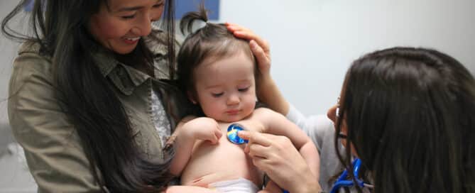 Toddler being examinded by a pediatrician while being held by her mother