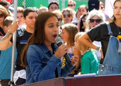Teen girl speaking into a microphone at a rally.