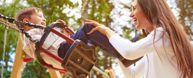 Woman pushing toddler on swing.