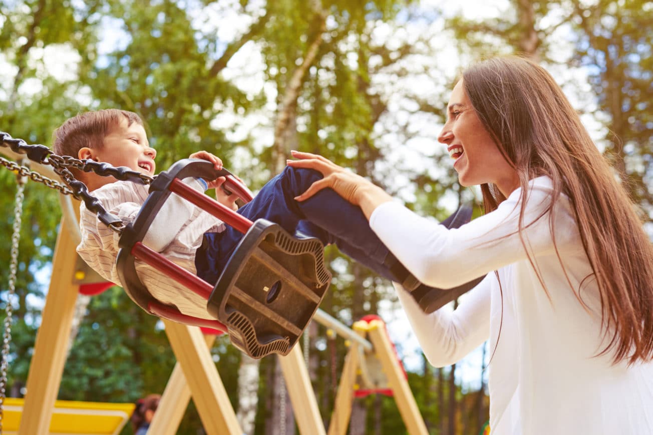 Woman pushing toddler on swing.