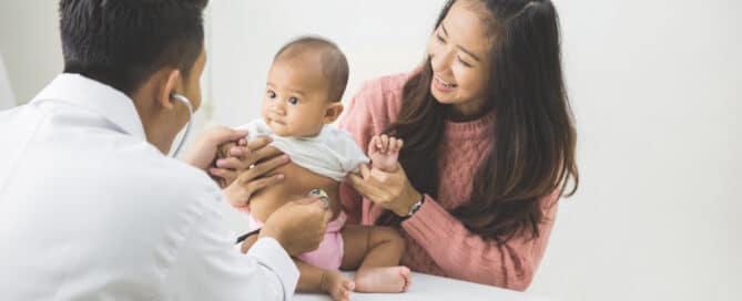 Small baby being held by mother at pediatrician's office.