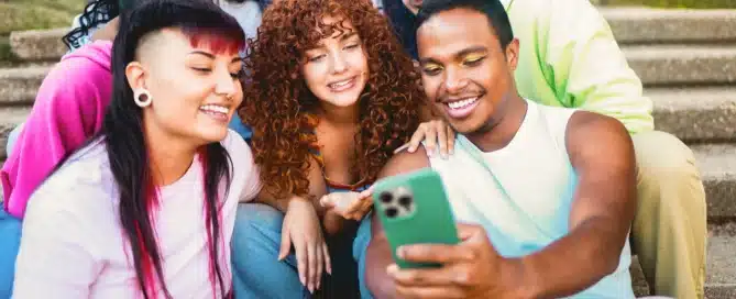 Young diverse people smiling at mobile phone camera at city park.