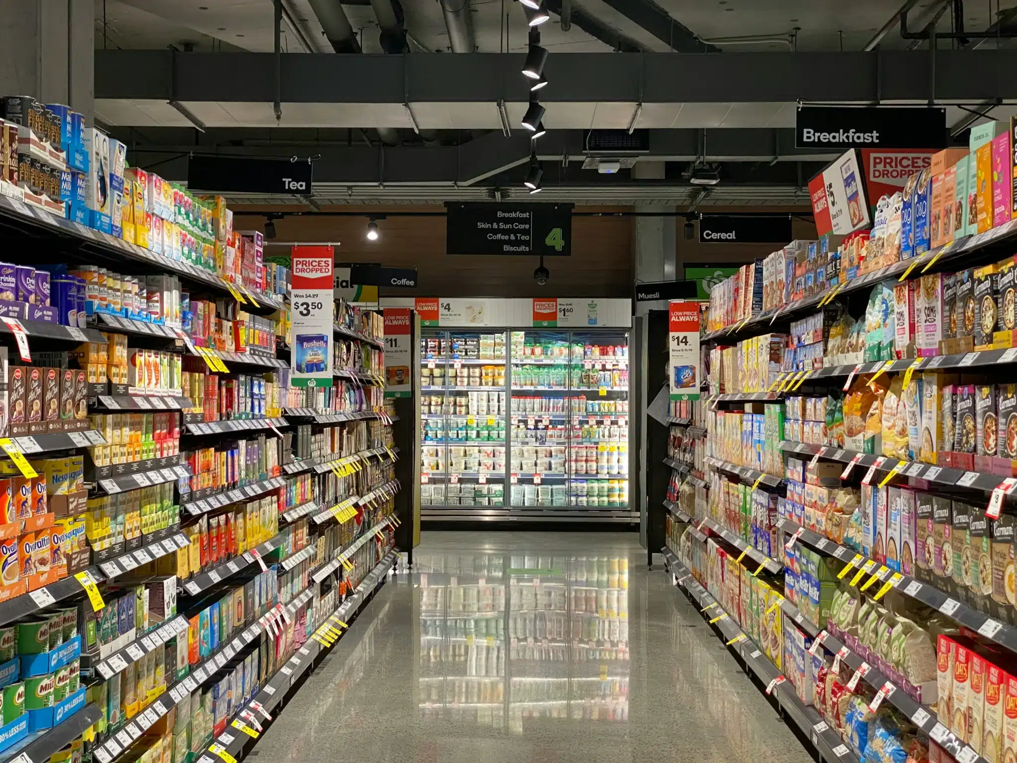 franki-chamaki-ivfp_yxZuYQ-unsplash Grocery store aisle lined with food-filled shelves facing the freezer