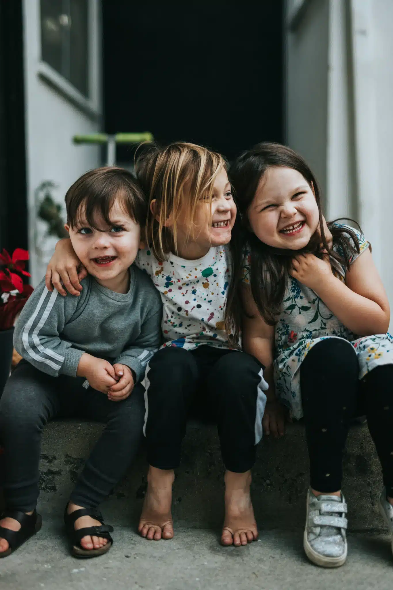 three kids with their arms around each other smiling