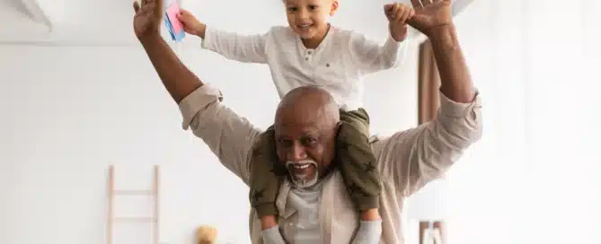 Best Grandfather. Cheerful Black Grandpa Carrying Little Grandson On Shoulders Playing And Having Fun Together At Home. Grandparent Spending Time With Happy Grandchild On Weekend