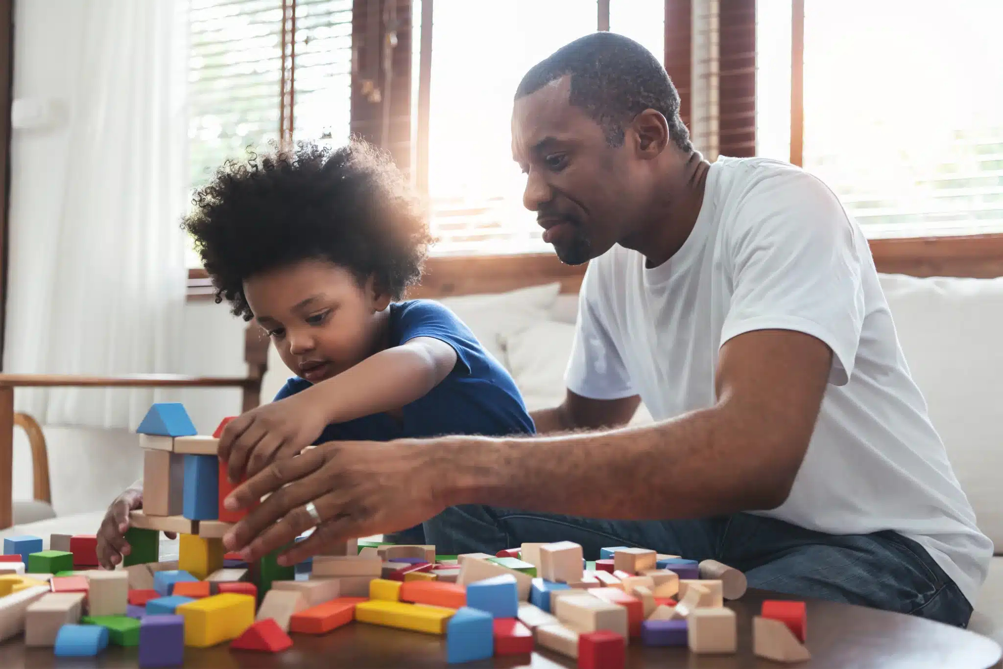 Happy father and toddler son playing together with blocks.