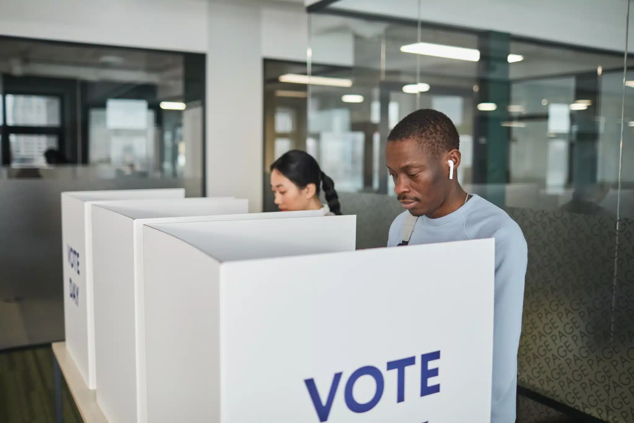 two people standing a poll booth casting their vote